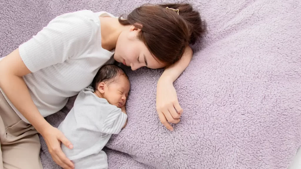 mãe e bebê deitados em um cobertor roxo