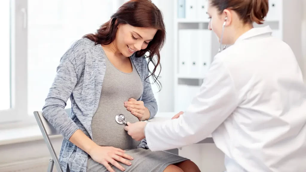 médica escutando com estetoscópio a barriga da gestante