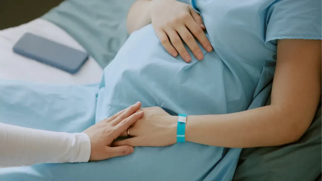 gestante com roupa hospitalar sendo consolada
