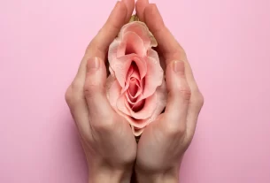 mãos feminina segurando uma flor rosa