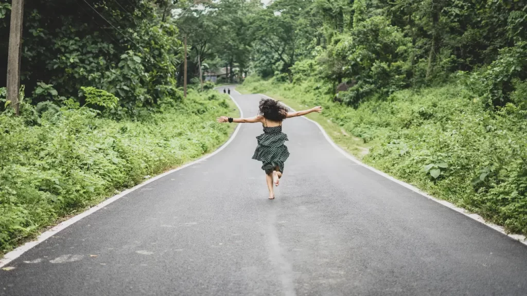 mulher correndo de braços abertos na estrada