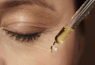 mulher passando um produto de beleza no olho