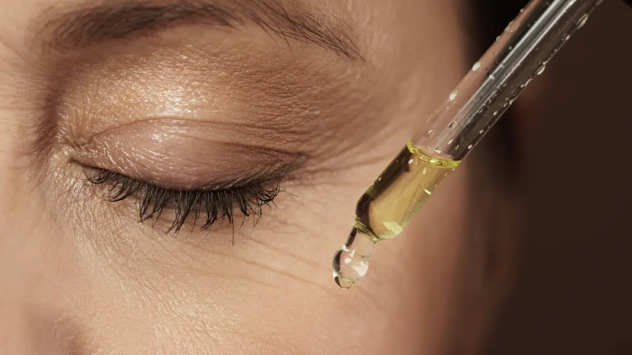mulher passando um produto de beleza no olho