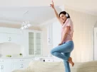 mulher dançando com fones de ouvido em cima do sofá
