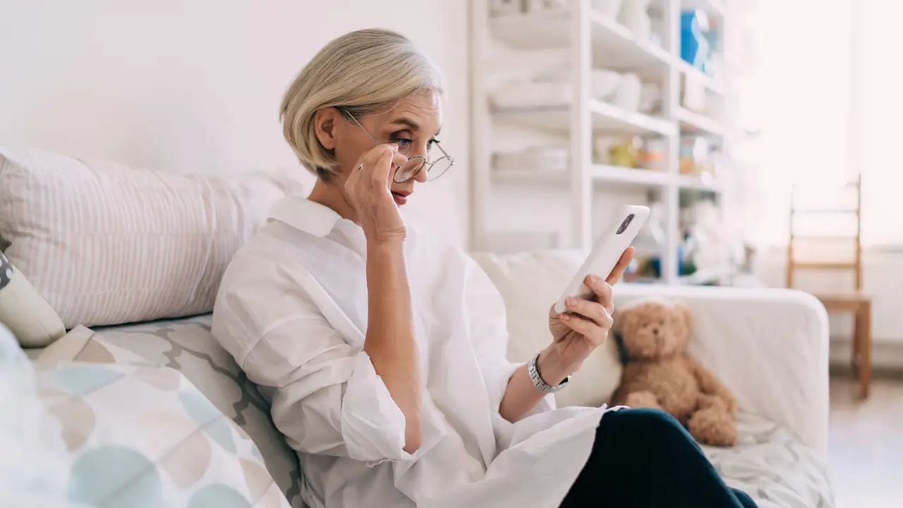 Mulher madura verificando perfil em app de relacionamento com cautela