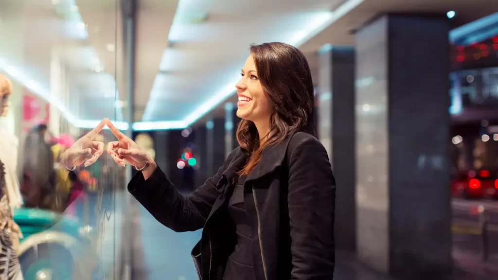mulher sorrindo olhando vitrine de loja