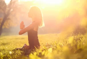 Mulher de 40 anos meditando em ambiente sereno com luz dourada, representando energia e vibração elevada