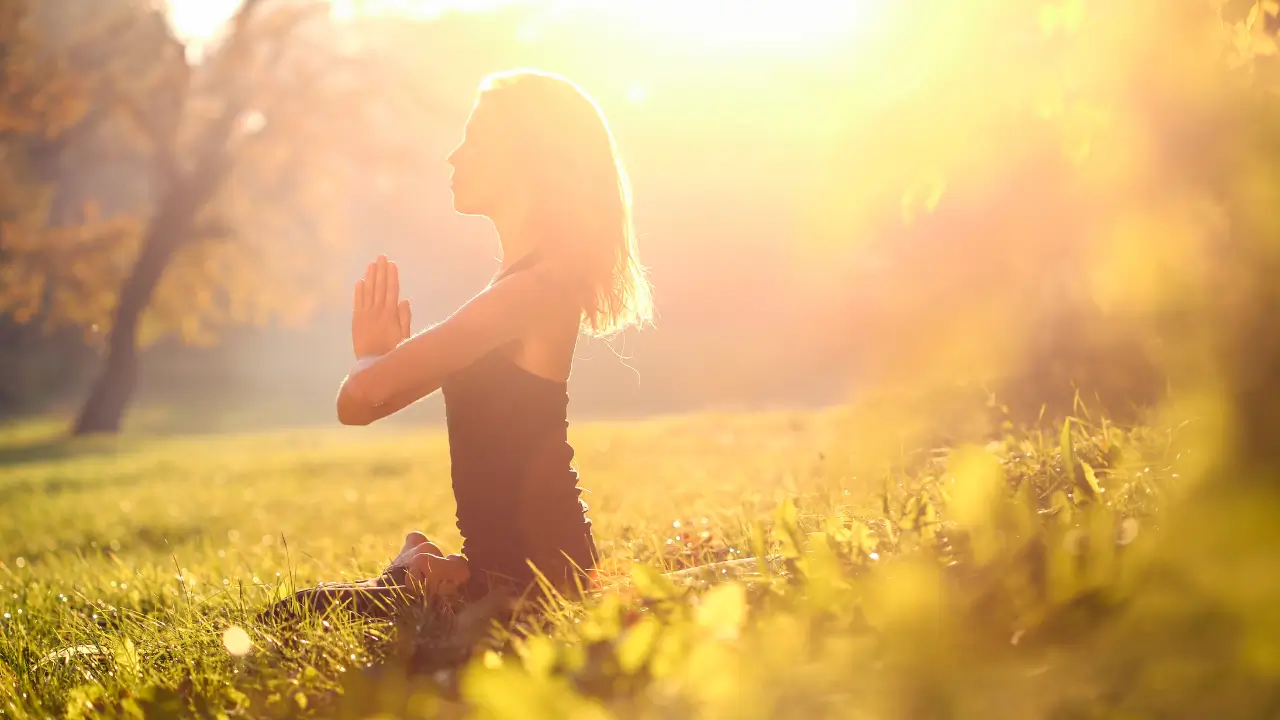 Mulher de 40 anos meditando em ambiente sereno com luz dourada, representando energia e vibração elevada