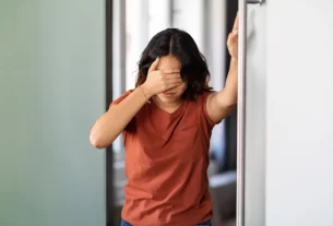 Mulher de 45 anos com mão na testa demonstrando tontura durante menopausa, ilustrando conexão entre hormônios e labirintite