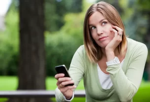 Mulher madura refletindo sobre posts motivacionais no smartphone