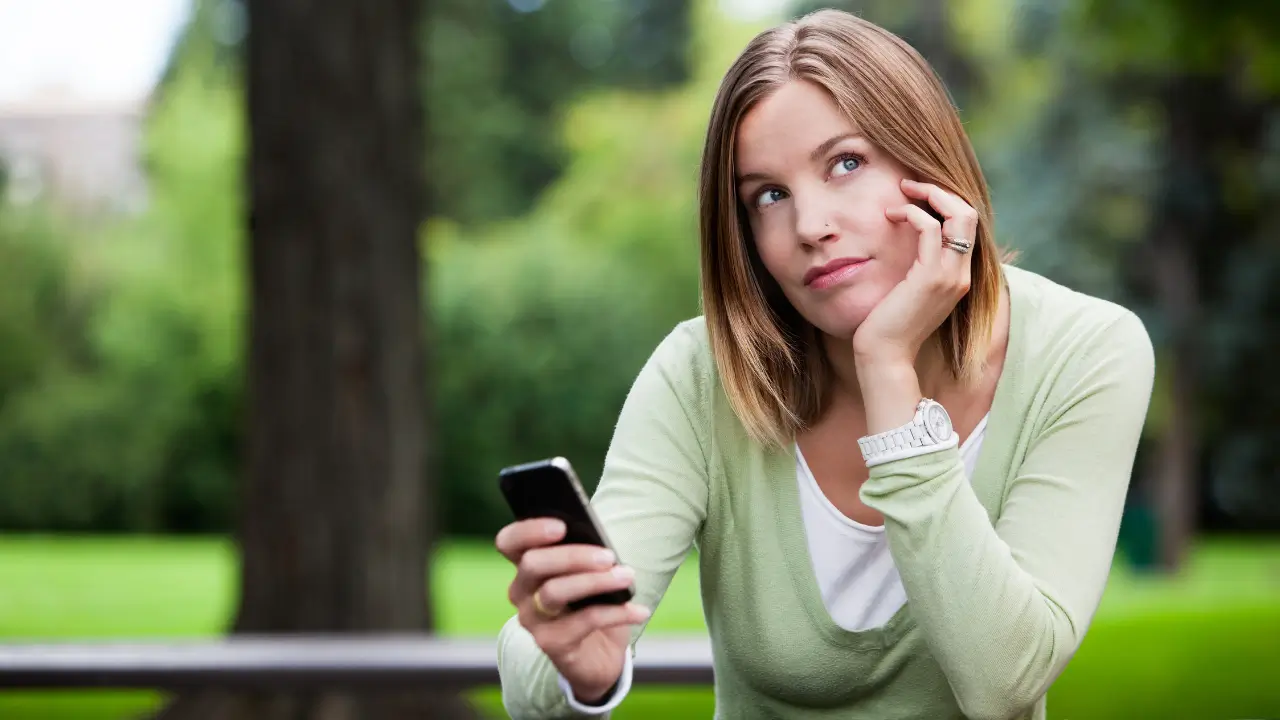 Mulher madura refletindo sobre posts motivacionais no smartphone