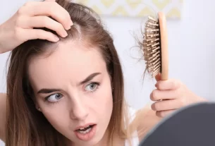 Mulher verificando queda de cabelo, sinal de que está comendo pouca proteína