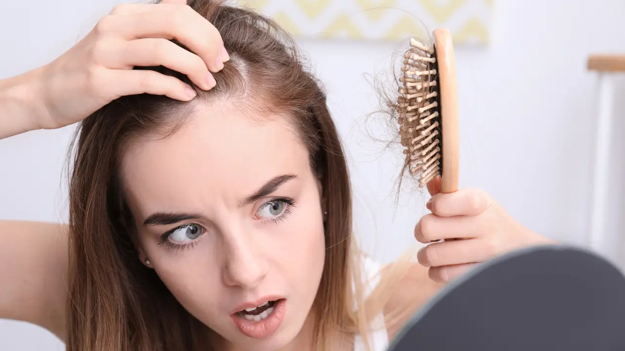 Mulher verificando queda de cabelo, sinal de que está comendo pouca proteína