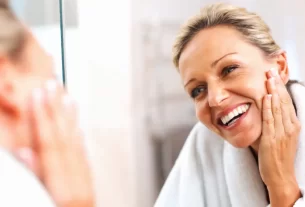 Mulher praticando autoaceitação na maturidade olhando-se com carinho no espelho