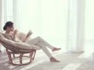 Mulher de 40 anos lendo livro em poltrona confortável demonstrando os benefícios de ler
