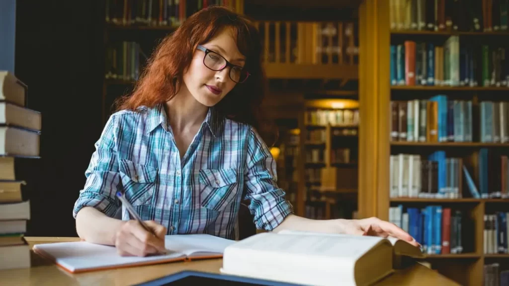 Mulher madura escrevendo reflexões sobre leitura em diário pessoal