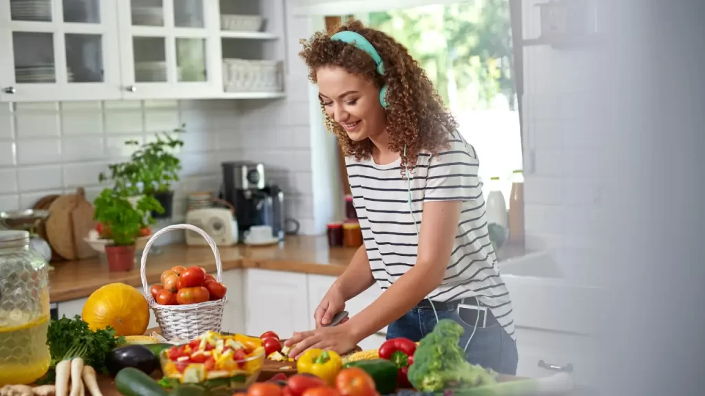 Mulher cozinhando e escutando música sorridente e animada